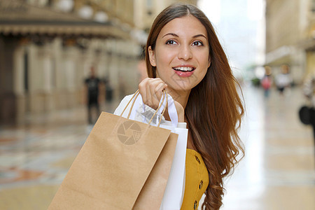 在意大利米兰手持购物袋的年轻时装女子微笑图片