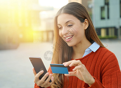 一个美女的肖像 拿着信用卡 在网上用户外智能手机买东西 而她却持有信用卡图片