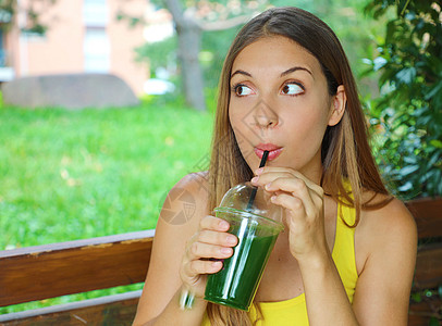 年轻美人喝绿色脱毒冰淇淋 健康女孩在健身后喝蔬菜粉凉水 体操锻炼图片