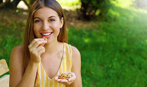 年轻女性在户外吃核桃 复制空间 健康食品概念图片