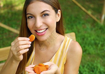 在公园里吃干果的年轻女子 健康的食物概念脱水坚果牙齿饮食小吃女士质量早餐营养女孩图片