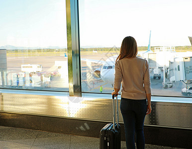 在现代机场候机站用手提箱看后背女青年图片