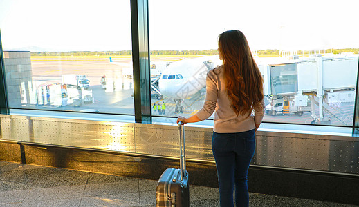 旅行旅游者与行李站在机场窗口看日落的旅客站立图片