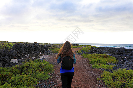 在兰萨罗特走的黑洞女性 年轻女子在西班牙火山加那利岛徒步旅行的后视线图片