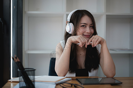 一个带着耳机的快乐女人 专注于她笔记本电脑上的网络研讨会视频互联网人士屏幕营销训练课程学习自由职业者员工图片