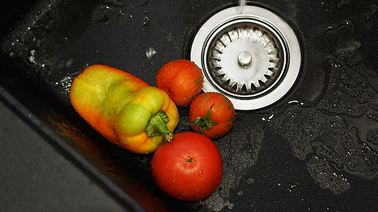 蔬菜     黑厨房水下水槽中的西红柿和胡椒洗涤反射飞溅运动食品背景食物花园液体黑色图片