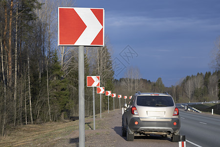 路标是向右急转弯 背景中的汽车停在路边图片