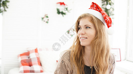 在诺姆的圣诞帽子上 有着迷人笑容的女人的肖像快乐展示惊喜女士微笑礼物房间女性假期头发图片