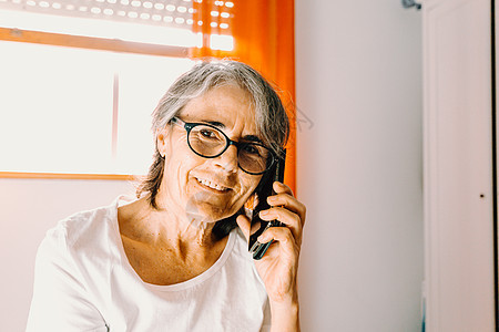 在卧室里微笑时 有个老太婆在电话上打来一通电话学习水平退休电子邮件老年手机长老客厅长椅社会图片