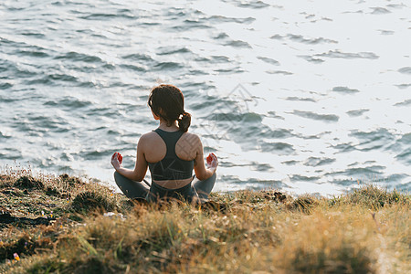 在野外海岸的岩石上做瑜伽 阳光明媚的一天 海面在前方 空间放松与和平的概念复制人间休息姿势练习训练太阳成人幸福女孩身体女士健康图片