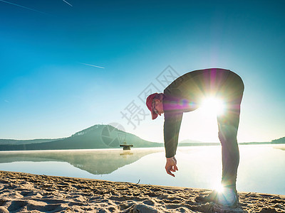年轻运动健壮的健身运动员在海滩上伸展身体和做瑜伽图片