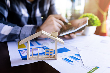脊柱模型商务人士或房地产代理使用计算器来计算房屋 贷款房屋 带房屋模型的投资物业的价格 房地产经纪人的概念背景