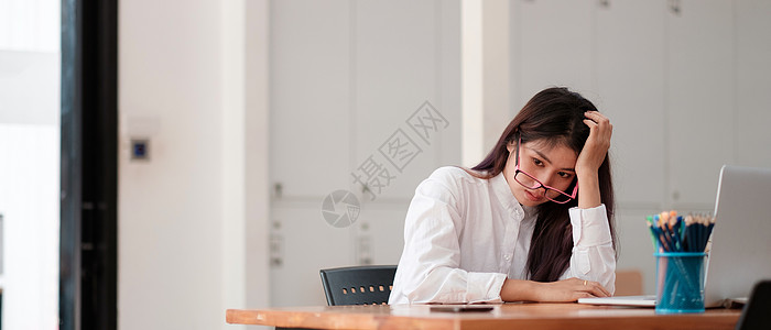 无聊的亚洲女工躺在办公桌前思考问题的解决方案 没有动力的女商务人士寻找灵感 厌倦了单调的工作 缺乏动机概念图片