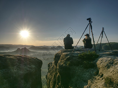 几位观光客拍摄山地和天空背景照片女士摄影师姿势夫妻爬坡旅游森林检查相机登山者图片