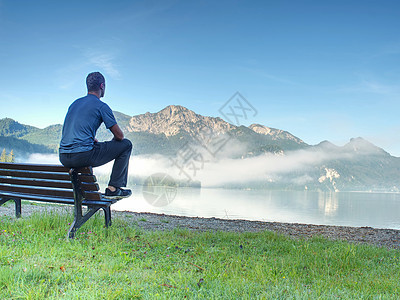 人类坐在湖边蓝山的白海边的木板凳上图片