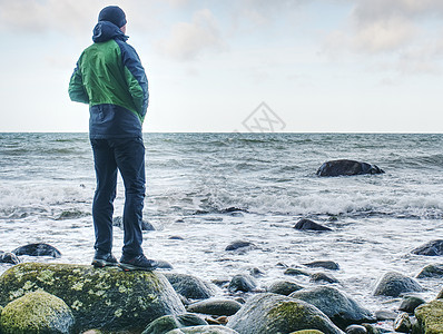 一个人站在海洋中间的岩石上 旅游者独自站立自由石头优胜者天空男性思维蓝色风险悬崖城市图片