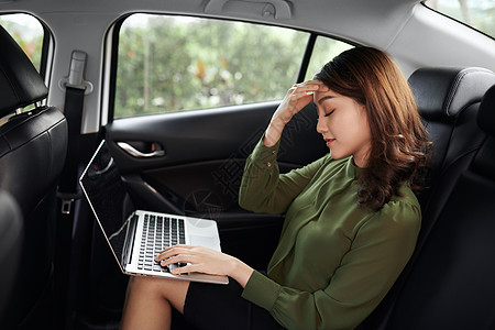 亚裔妇女在坐在车里时用笔记本电脑做无聊的心理压力工作图片