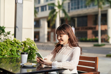 街头咖啡馆的迷人女人 在读她的手机短信时看一眼图片