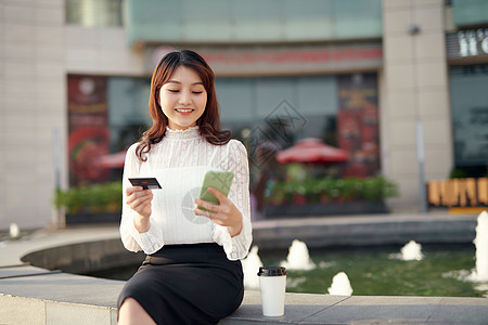 手持智能手机并用信用卡支付货品工资的女子图片