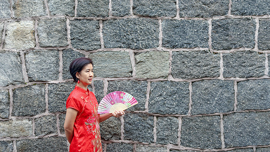 穿中国传统石墙服装的单身女旅游女性游客折扇民族假期民间戏服女士衣服新年幸福旅行图片