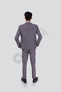 穿着西装的年轻亚洲商务人士的后视图手插在口袋里 自信地孤立在白色背景上 商务人士的背后是经理或高管或员工 他们在思考成功 全长职图片