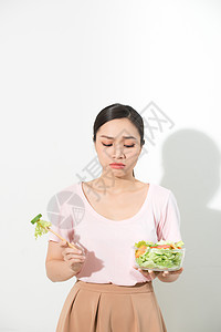 不快乐的亚洲女性正在节食 女孩不想吃蔬菜 不喜欢蔬菜的味道食欲白色损失营养厌恶女士食物饮食图片
