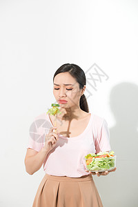 不快乐的亚洲女性正在节食 女孩不想吃蔬菜 不喜欢蔬菜的味道早餐营养女士玻璃绿色饮食食物白色图片