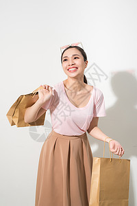 微笑着的年轻女子拿着购物袋 笑着对在白色上被孤立的照相机微笑女性女孩幸福裙子假期销售庆典粉色店铺女士图片