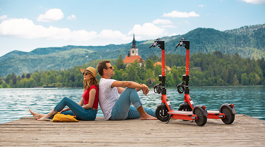 年轻夫妇在假期探索绿色国家斯洛文尼亚时 使用电动滑板车作为现代生态交通工具 零排放的绿色生态能源理念 温暖的阳光过滤器旅游乐趣夫图片