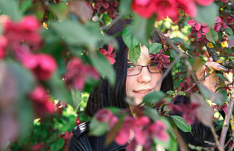 樱花附近年轻女孩的肖像女性头发夹克眼镜毛衣黑发成人公园花园图片