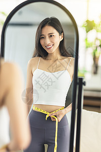 年轻妇女用测标尺测量纸张 在镜子中测量腰部大小 对减重的结果和当前数字非常满意 单位 千分之一至四舍五入运动节食女士组织生活方式图片