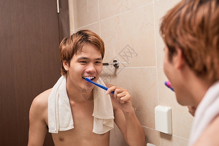 清晨刷牙 有吸引力的年轻人用牙刷刷牙 照镜子看自己 笑声保健浴室男性卫生牙齿刷子白色口服男人镜子图片
