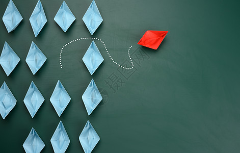 一组蓝色的纸船朝一个方向航行 一只红色的朝相反的方向航行创造力商业领导者解决方案领导折纸个性绿色竞赛舰队图片