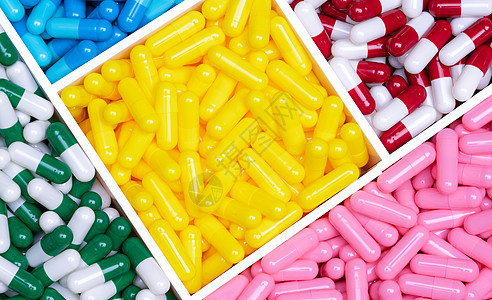 塑料托盘中的顶视图彩色胶囊药丸 黄色 粉色 红色 绿色和蓝色胶囊药丸 抗生素 维生素和补充剂胶囊 医药行业 处方药背景图片