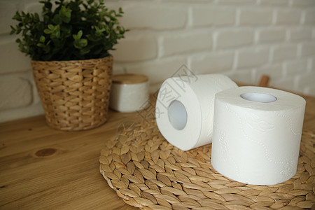 在一张木桌上的卫生纸 两个白卷 砖背景 一朵绿花 白色和米色地面回收洗手间家庭床单卫生清洁工厕所管子设施图片