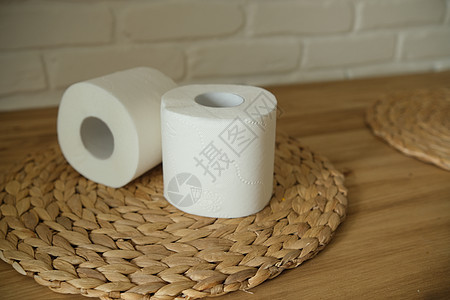 在一张木桌上的卫生纸 两个白卷 圆形编织垫 米色 白色砖墙背景卫生洗手间床单清洁工屁股配件柔软度设施厕所卫生间图片