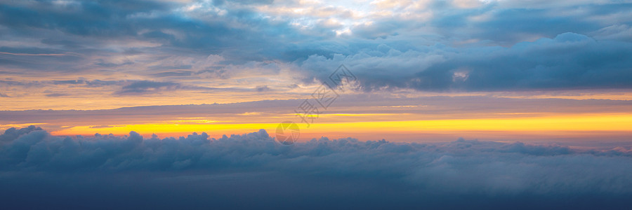 美丽的夕阳天空在云层之上 散发着戏剧性的光芒 从飞机上看机舱 飞翔在云层之上 从飞机上看 与日落的美好的蓝天背景 云层之上的日落图片