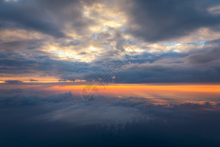 美丽的夕阳天空在云层之上 散发着戏剧性的光芒 从飞机上看机舱 飞翔在云层之上 从飞机上看 与日落的美好的蓝天背景 云层之上的日落图片