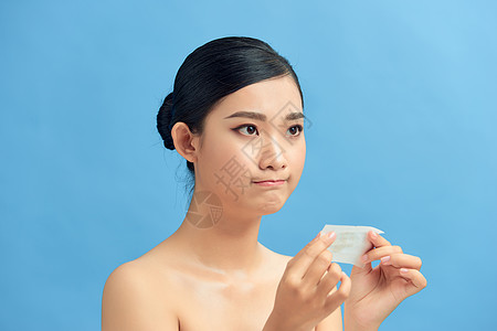 韩国皮肤管理年轻年幼的亚洲皮肤护理女性在脸上涂油纸后心烦意乱控油印迹床单化妆品女孩光泽控制产品女士背景