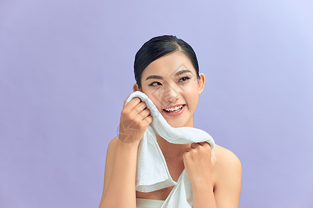 美丽快乐笑笑的年轻的年轻女性模特 用软毛巾擦面部皮肤 除掉化妆品清洁辉光温泉打扫毛巾女士质量白色背景图片