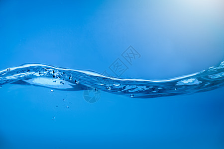 清澈的蓝色水里有气泡的水浪背景图片