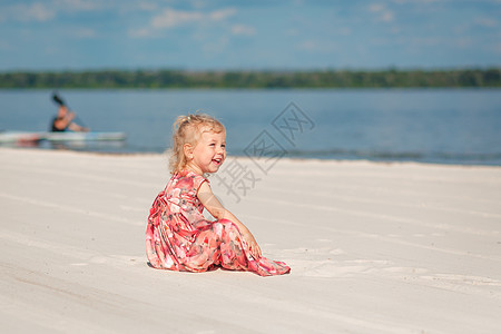 一个穿着漂亮的 sarafna 的小女孩在沙滩上的沙子里玩耍享受假期帽子天空婴儿支撑喜悦晴天海岸线太阳图片