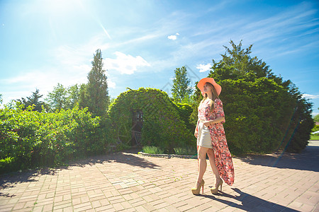 穿着淡夏日服的迷人女孩和佩雷奥帽正在绿色公园行走 享受阳光明媚的暑假幸福花园女性闲暇公园太阳成人舞蹈草地晴天图片