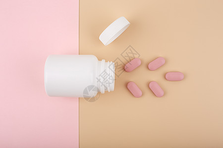期待有你白色打开的药瓶 上面有粉色溢出的药丸 背景是柔和的粉色和米色背景