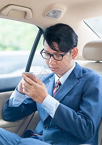 商务人士在汽车里电话上说话机动性技术眼镜运输出租车经理领带乘客奢华手机图片