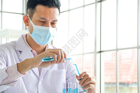 亚洲科学家或化学家对实验室中蓝色液体化学品滴子进行实验 试验地点样本化学研究员生物科学诊所技术显微镜男人测试图片
