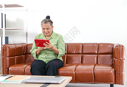 在客厅里用智能手机 校对 Portnoy桌木沙发互联网商业人士老年技术笔记本退休商务背景图片