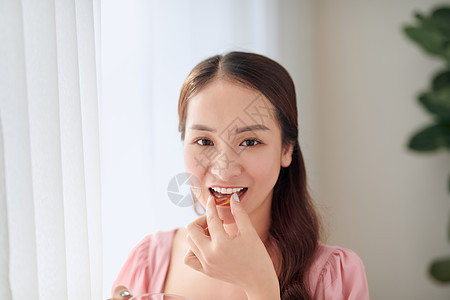 年轻美丽的亚洲妇女 吃药丸和饮用水药片药品药店饮食女士疼痛玻璃女孩胶囊女性背景图片