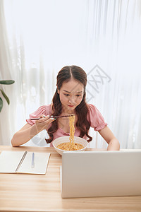 年轻亚洲女孩在家吃面时使用笔记本电脑优胜者庆典办公室商业乐趣休息女士胜利午餐筷子背景图片
