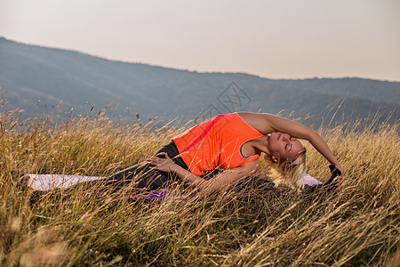 在自然界做瑜伽的漂亮女人太阳天空成人教练运动练习身体生活方式女士运动装图片